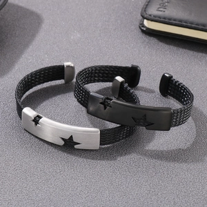 Macro detail of brushed metal cuff bracelet with star cutout and woven fiber strap