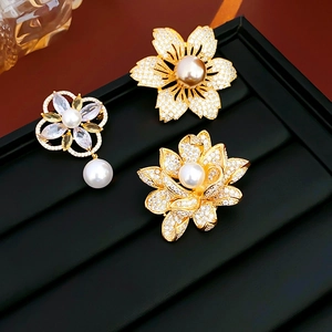 Detailed view of floral brooches with gold plating, pearls and zircon on black velvet