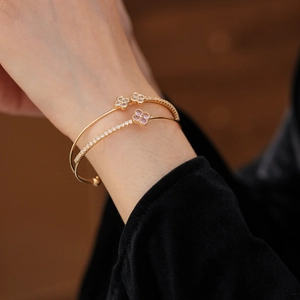 Detailed view of gold double-layer clover bangle featuring zircon stones on female wrist