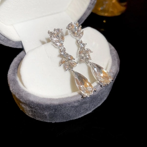 Macro shot of silver drop tassel earrings with leaf pattern in a velvet jewelry box