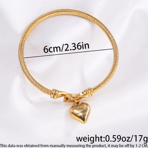 Detail of a golden twisted cable bangle with heart charm and 'I Love You' engraving