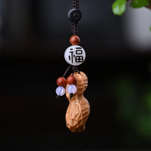 Macro detail of hand-carved wood peanut pendant with lucky Fu character bead on charm