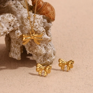 Detail of 18K gold plated stainless steel bow necklace and earrings set on sea shells