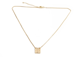 Detailed close-up of golden square pendant with religious relief and thin lobster clasp chain