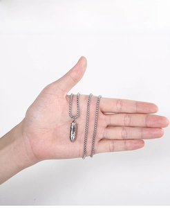 Pendentif balle en argent avec chaîne fine tenu en main montrant les détails vintage