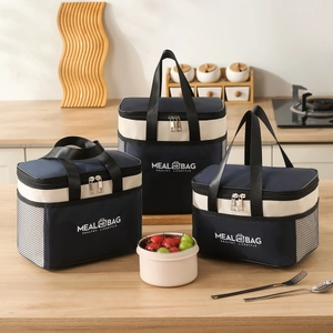 Three navy and cream insulated meal bags with handle on a wooden kitchen countertop