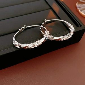 Macro shot of silver twisted hoop earrings with shimmering crystals on black leather