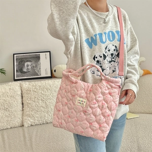 Close-up of pink quilted crossbody bag with floral and bunny patterns in home setting