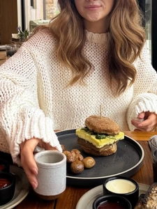 Close-up of cozy cream knit sweater featuring chunky cable pattern and relaxed high neckline