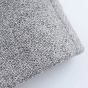 Close-up of grey tweed wool fabric texture showing intricate woven fiber patterns