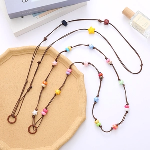 Colorful acrylic star bead crossbody phone lanyard with brown woven rope on a beige tray