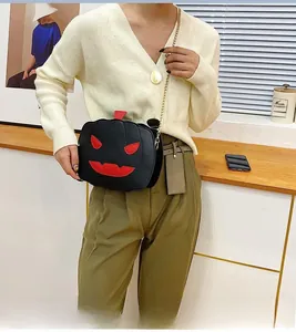 Close-up of pumpkin shoulder bag with red devil face applique and metal chain strap