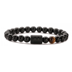 Detail of black beads bracelet with tiger eye stone and Gemini zodiac cylinder charm