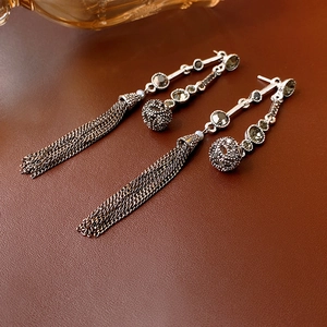 Dettaglio di eleganti orecchini a nappa d'argento con catene metalliche e cristalli