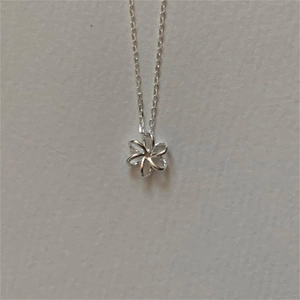 Detailed top-down shot of a small silver flower pendant with a delicate fine chain necklace