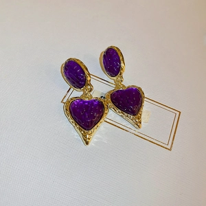 Close-up of vintage heart earrings with purple textured resin and gold-plated frames