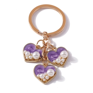 Rose gold heart keychain with purple textured charms and white pearls on white background