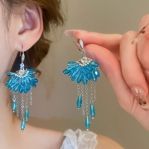 Detail of fan-shaped crystal earrings with blue petals and long silver tassel fringe