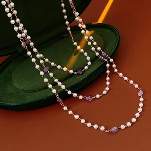 Detail of vintage gold necklace with white pearls and purple amethyst on velvet box