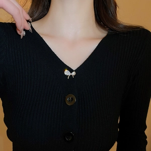 Élégante broche nœud en zircon plaqué or épinglée sur un pull noir à col en V pour femme