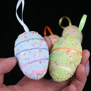 Close-up of colorful foam Easter eggs with hanging ribbons and textured glitter surface