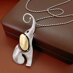 Vue macro d'un pendentif éléphant bicolore argent et or sur une boîte à bijoux en cuir