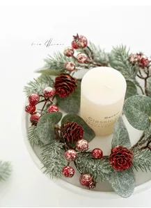 Nahaufnahme von Weihnachtskerzenkranz mit roten Beeren, Zapfen und weißer Stumpenkerze