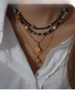 Detail of layered gold necklace with colorful natural stones, pearls and coin pendants