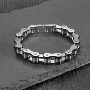 Men's silver and black stainless steel bicycle chain bracelet on dark slate background