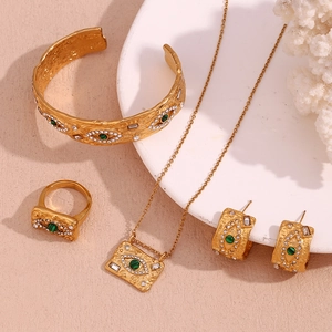 Detail view of gold evil eye jewelry set with green stones and hammered texture