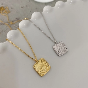 Minimalist S925 silver leaf necklaces in gold and silver finish on a ceramic plate