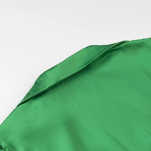 Detail of green satin top showing high-quality stitching and smooth fabric texture