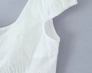 Dettaglio del top in cotone bianco con ricamo sangallo e rifiniture delle cuciture