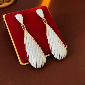 Détail de boucles d'oreilles vintage goutte avec rayures dorées sur velours rouge