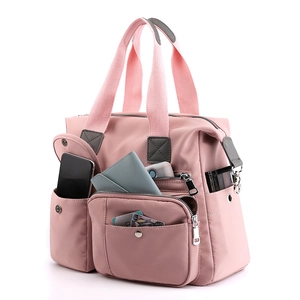 Roze nylon shopper tas detail met meerdere functionele buitenzakken en stevige handvatten.