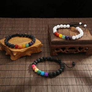 Dettaglio dei braccialetti chakra in pietra lavica da 8mm su supporto in legno