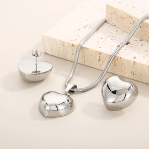Polished silver heart jewelry set featuring necklace and earrings on stone pedestals