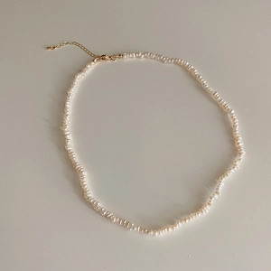 Detailed macro view of baroque freshwater pearl necklace with adjustable gold lobster clasp