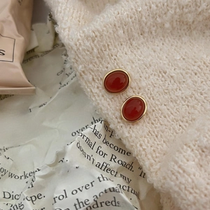 Detail view of 925 silver red agate stud earrings on cozy beige knit fabric background