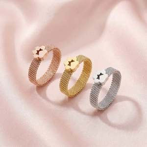 Detailed macro of woven mesh rings featuring star cutout flower motifs on pink silk