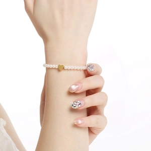 Elegant French vintage pearl bracelet with gold heart charm shown worn on a lady wrist