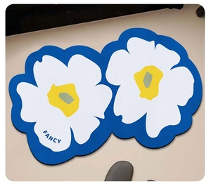 Close-up of a flower-shaped blue bath mat featuring the fancy typography on petals