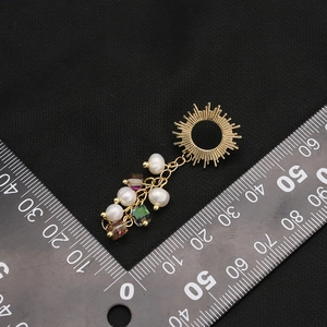 Handmade 18k gold sun pendant with freshwater pearls and beads on black knit background