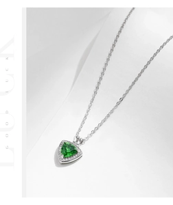 Macro detail of geometric necklace featuring a green emerald-cut triangle pendant