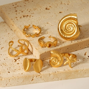Golden ocean theme rings set with shell starfish and dolphin motifs on stone stand