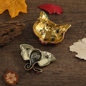 Golden plated vintage elephant and owl brooches showing pin back details on wood surface