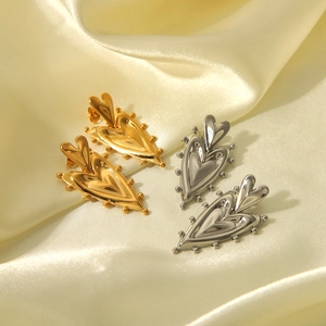 Polished double-layered heart drop earrings in gold and silver on silk background