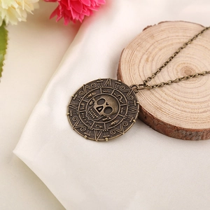 Bronze Jack Sparrow skull coin necklace displayed on wood with soft floral background