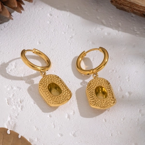 Detailed view of gold hammered oval earrings with elegant natural pine cone accents
