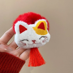 Detailed macro view of plush lucky cat embroidery with vibrant red tassel for hair ties